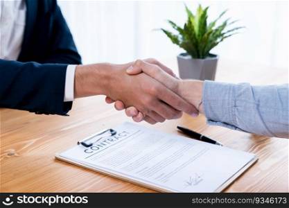 Two business people shake hand after successfully signing contract agreement in corporate office with legal document and pen on the table symbolizes business partnership and cooperation. Entity. Two business people shake hand after successfully signing contract. Entity