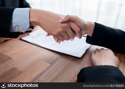 Two business people shake hands after successfully signing contract agreement in corporate office with contract document and pen on table. Legal paper and business partnership concept. Jubilant. Two business people shake hands after successfully signing contract. Jubilant