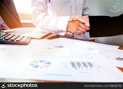 two business people shaking hands while sitting at the working place
