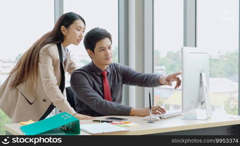 Two business people talk project strategy at office meeting room. Businessman discuss project planning with colleague at modern workplace while having conversation and advice on financial data report.