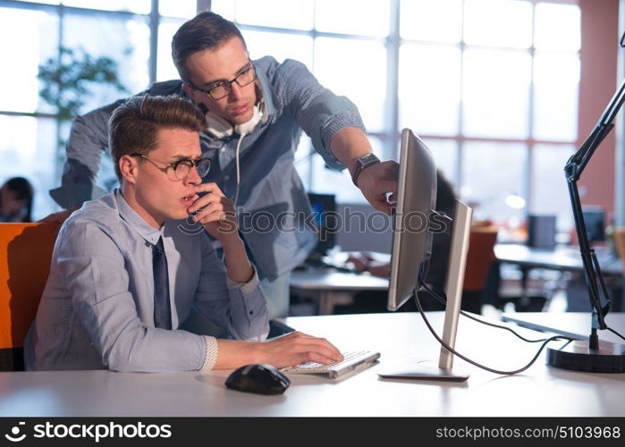 two business people using computer preparing for next meeting and discussing ideas with colleagues in the background