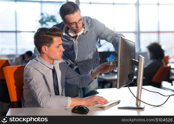 two business people using computer preparing for next meeting and discussing ideas with colleagues in the background