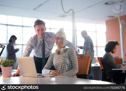 two business people using laptop preparing for next meeting and discussing ideas with colleagues in the background