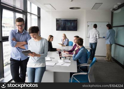 two business people using tablet preparing for next meeting and discussing ideas with colleagues in the background