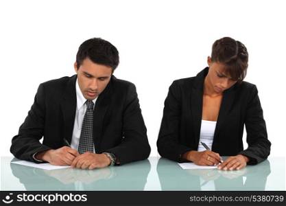 Two business people writing at a desk
