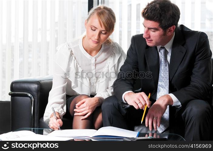 two business persons are sitting and discussing on leather sofa at office