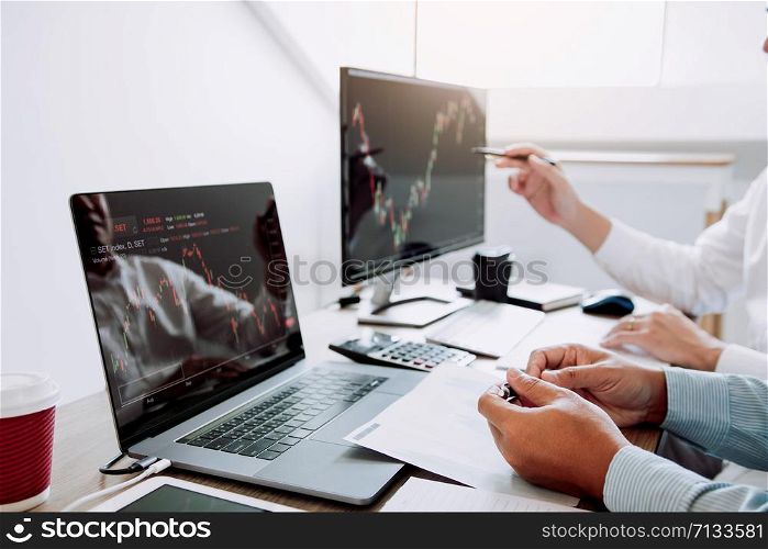 Two business stock brokers stress and looking at monitors displaying financial stock graph report information.