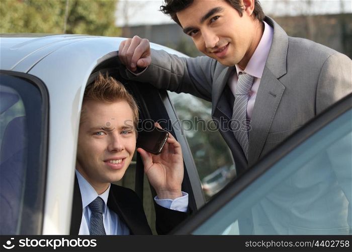 Two businessman by a car.