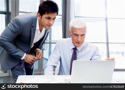 Two businessman in office having discussion in front of computer. Ready to help