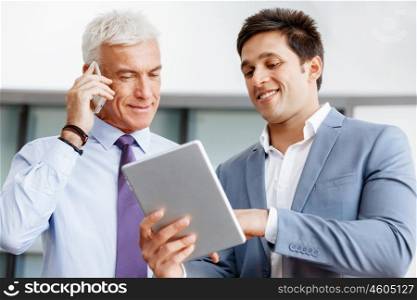Two businessman in office with devices. Discussion and technology give way to solution