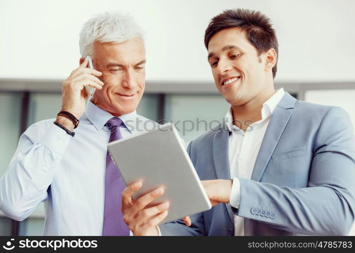 Two businessman in office with devices. Discussion and technology give way to solution