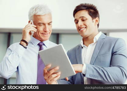 Two businessman in office with devices. Discussion and technology give way to solution