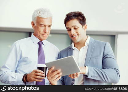 Two businessman in office with devices. Discussion and technology give way to solution