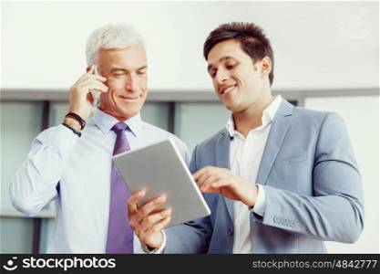 Two businessman in office with devices. Discussion and technology give way to solution