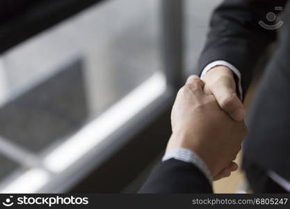 two businessman in suit shaking hands beside window - business teamwork, cooperation concept