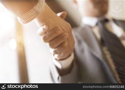 two businessman in suit shaking hands beside window - business teamwork, cooperation concept