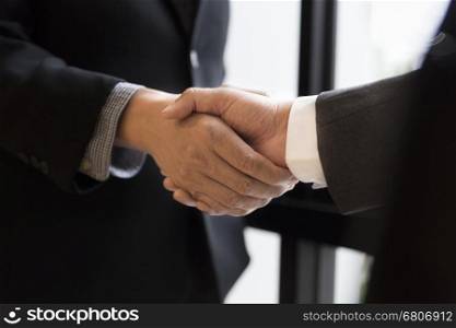 two businessman in suit shaking hands beside window - business teamwork, cooperation concept