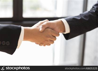 two businessman shaking hands beside window - business teamwork, cooperation concept