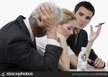 Two businessmen and a businesswoman at a meeting in a conference room