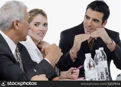 Two businessmen and a businesswoman at a meeting in a conference room