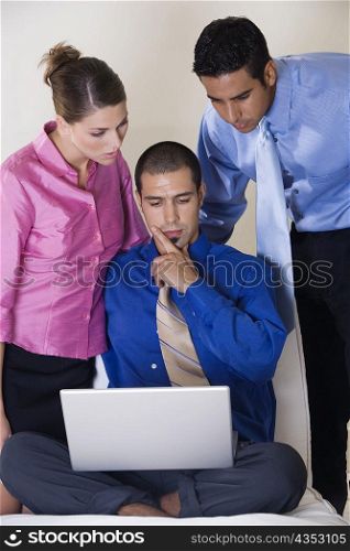 Two businessmen and a businesswoman in front of a laptop