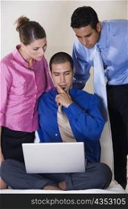 Two businessmen and a businesswoman in front of a laptop