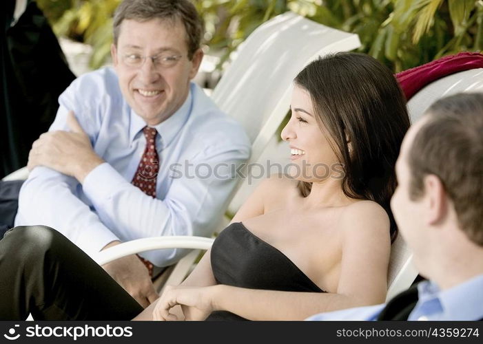 Two businessmen and a businesswoman sitting on lounge chairs