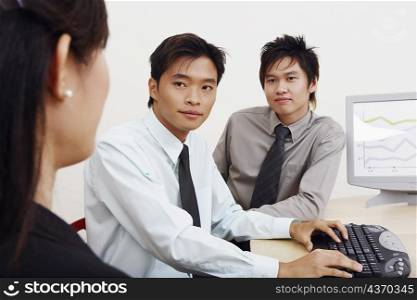 Two businessmen and a businesswoman sitting together in an office