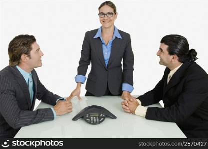 Two businessmen and a businesswoman smiling in a board room