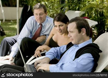 Two businessmen and a businesswoman working on a laptop