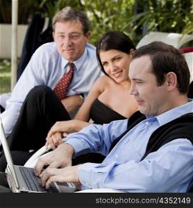 Two businessmen and a businesswoman working on a laptop
