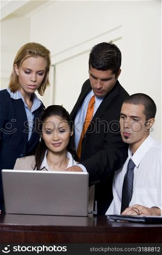 Two businessmen and two businesswomen in front of a laptop