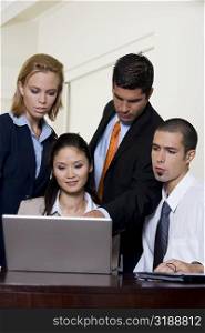 Two businessmen and two businesswomen in front of a laptop