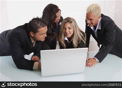 Two businessmen and two businesswomen using a laptop