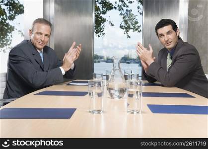 Two businessmen applauding in a conference room