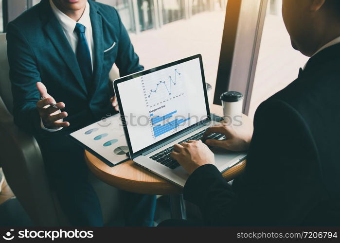 Two businessmen are talking about the results of operations in the company financial statements on the computer screen.