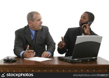 Two businessmen at desk interupted by phone call.