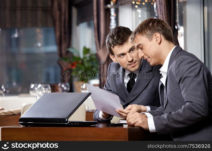 Two businessmen at restaurant discuss the document
