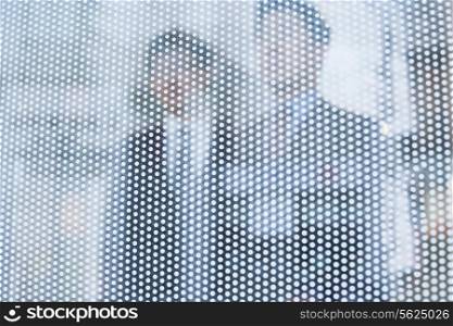 Two businessmen behind a glass wall looking out, unrecognizable faces