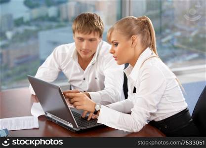 Two businessmen behind a table looking in the laptop