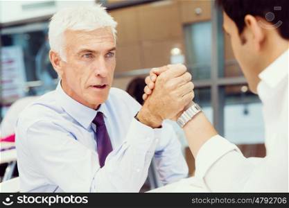 Two businessmen competeting arm wrestling in office. Who is the leader