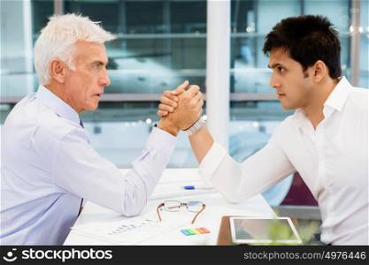 Two businessmen competeting arm wrestling in office. Who is the leader