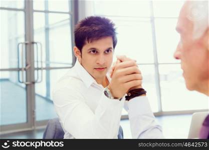 Two businessmen competing arm wrestling in office. Who is the leader