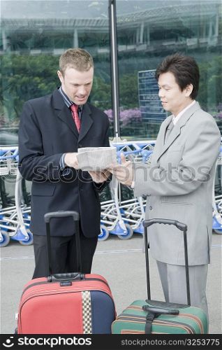 Two businessmen discussing a document outside an airport