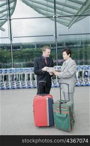 Two businessmen discussing a document outside an airport
