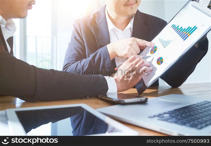 Two businessmen discussing the charts and graphs showing the results of their successful project .Digital tablet ,smart phone and laptop computer using .Business finances and accounting concept.