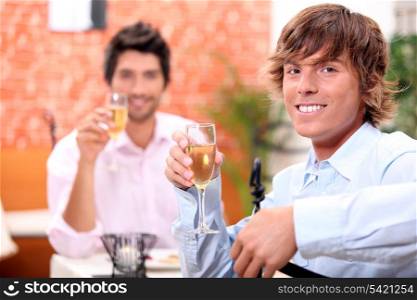 Two businessmen drinking champagne in restaurant