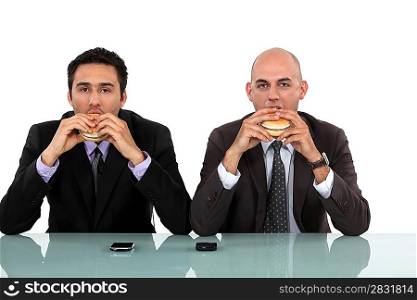 Two businessmen enjoying a burger.