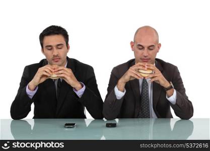 Two businessmen enjoying hamburgers