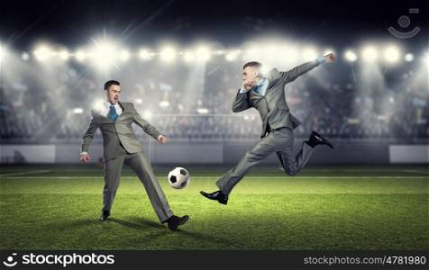 Two businessmen fight for ball. Young businessman in suit playing football at stadium
